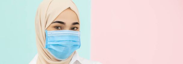 Donna musulmana che indossa maschera medica per prevenire il virus dell'infezione su sfondo di colore pastello. Concetto di Coronavirus (covid-19)
 - Foto, immagini