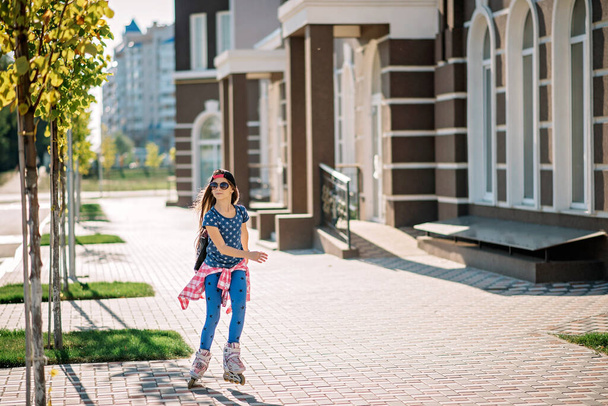 Girl rollerblading on a city street on a bright summer sunny day. Sports recreation. Healthy lifestyle. - Фото, зображення