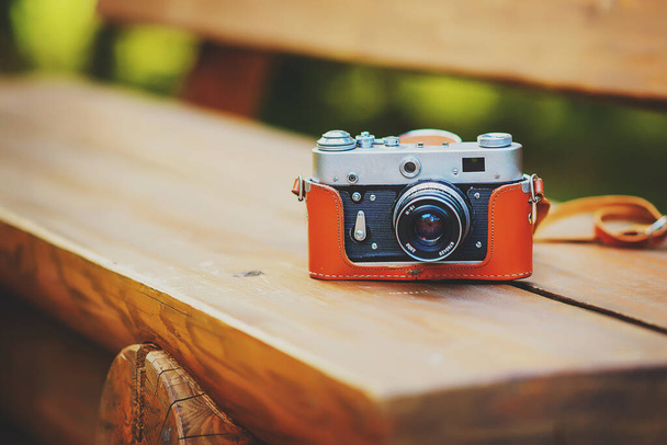 old retro camera on a wooden bench in a sunny green forest - Photo, Image