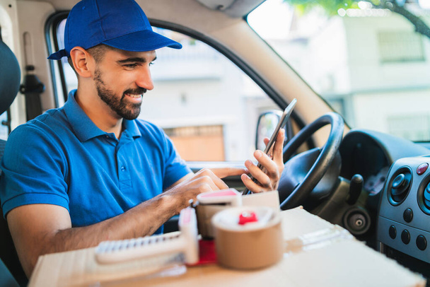 Portrait of a delivery man driver using digital tablet while sitting in van. Delivery service and shipping concept. - Φωτογραφία, εικόνα