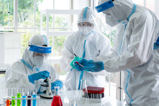 scientists in personal protective equipment or ppe doing research and experiment to find drugs to treat covid-19 or coronavirus infection in the lab - Photo, Image