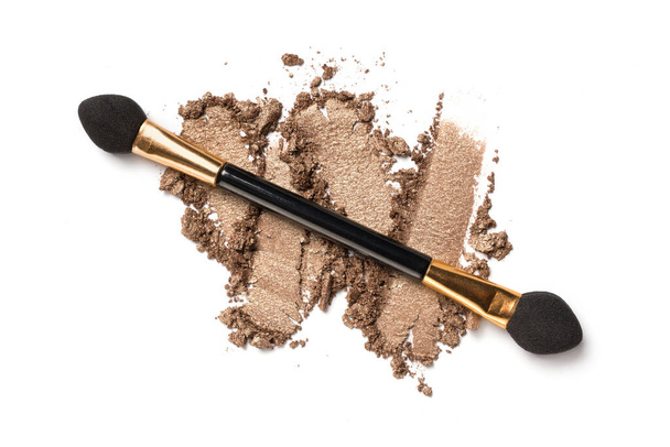 Flat lay of brush stroke. Broken shiny brown or bronze color eyeshadow as sample of cosmetic beauty product isolated on white backgroun - Φωτογραφία, εικόνα