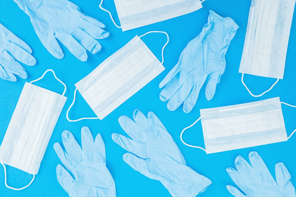 Медицинские маски и перчатки для защиты от вирусов и бактерий на синем фоне. Эпидемия с маской и перчатками. Плоский лежал. Вид сверху
 - Фото, изображение