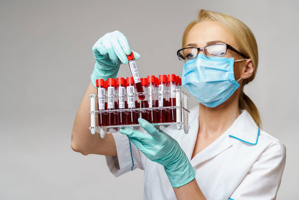 medical doctor nurse woman wearing protective mask and gloves - holding rack with virus blood tests - Photo, image