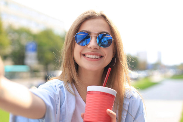 Trendy cool hipster girl drink cocktail in urban city background - Fotó, kép