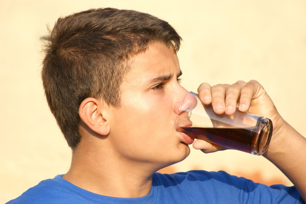 Un adolescente está bebiendo una coca de vidrio.
 - Foto, imagen