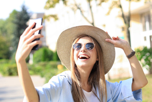 Krásná mladá blondýna dívka pomocí mobilního telefonu při stání venku - Fotografie, Obrázek