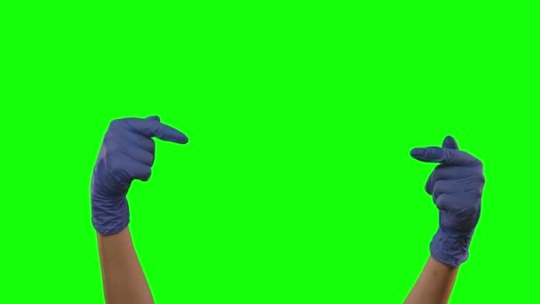 Hands in blue gloves gesturing showing pointing with index fingers on something with copy space. Green screen. Close up - Imágenes, Vídeo