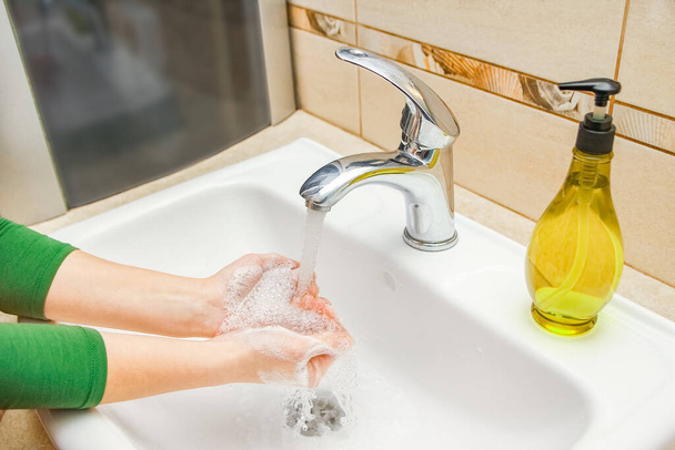 Le mani con sapone vengono lavate sotto il rubinetto con acqua. Pulito da infezioni e sporcizia e virus. A casa o in ospedale ufficio abluzione. - Foto, immagini