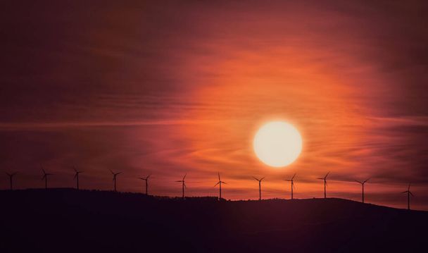 Гарний схід сонця з вітровими турбінами на пагорбі
. - Фото, зображення