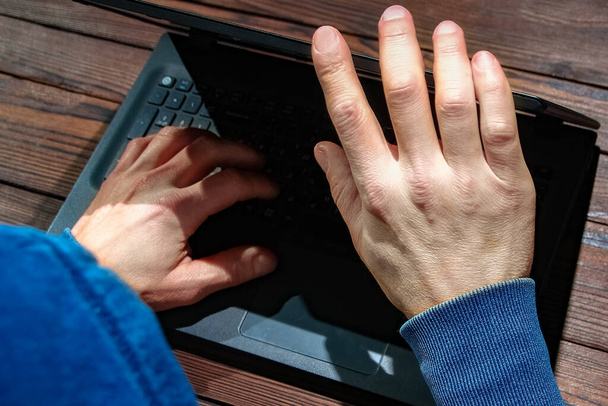 Hacker con portátil se sienta en una mesa y el código binario abstracto. Programas virtuales de amenaza para la vida empresarial. - Foto, imagen