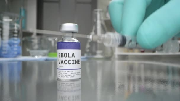 Szczepionka przeciwko eboli z umieszczoną obok strzykawką powoli przechodzącą obok butelki w laboratorium przyśrodkowym. - Materiał filmowy, wideo