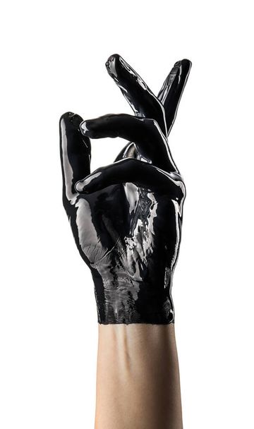 Κομψό γυναικείο χέρι σε μαύρο λατέξ γάντι σε λευκό φόντο. Γυναικείο χέρι σε υγρό μαύρο λάδι ή μαύρο ακρυλικό χρώμα - Φωτογραφία, εικόνα