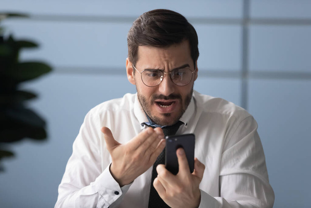 Frustrated businessman angry over bad news message on smartphone. - Foto, imagen
