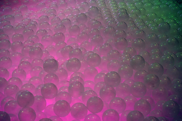 Piscina de bolas transparentes con humo rosa y verde que sube desde abajo
. - Foto, Imagen