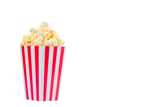 Popcorn in red and white striped cardboard bucket isolated on white background. Movie Popcorn isolated on white with clipping path. Tasty salted popcorn in striped paper cup . - Foto, Bild