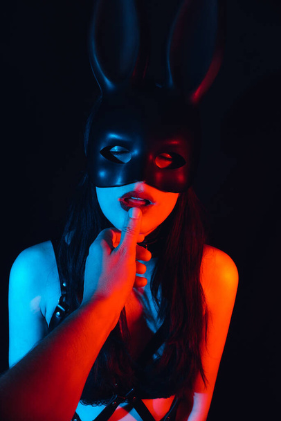 macho dominante toca los labios de una sumisa hermosa chica en una máscara de conejo
 - Foto, imagen