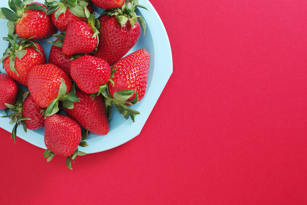Teller mit frischen Erdbeeren auf blauem Hintergrund, Draufsicht mit Kopierraum - Foto, Bild