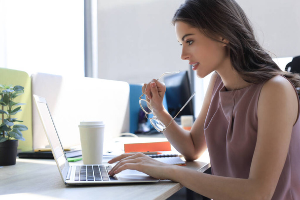 Beautiful business woman in smart casual wear working on laptop in the office. - Фото, зображення