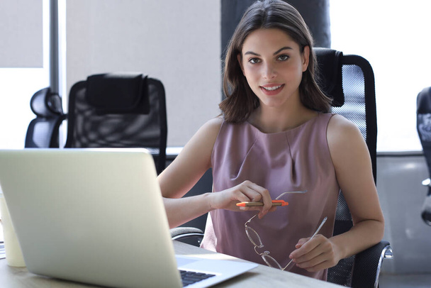 Beautiful business woman in smart casual wear working on laptop in the office. - 写真・画像