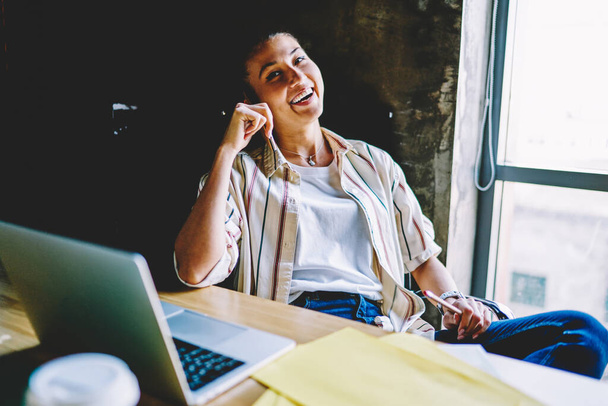 Cheerful young woman sitting at desktop with laptop computer satisfied with freelance business, smiling successful female employee laughing during working process enjoying great idea for publicatio - Photo, Image