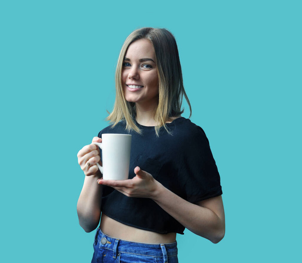 Blonde girl in a black T-shirt with a white mug - Foto, afbeelding