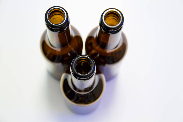 Καφέ και πράσινα μπουκάλια μπύρας σε λευκό φόντο. Ποτά και μπύρα σε ένα τέλειο μπουκάλι. Με διαφορετική εστίαση.  - Φωτογραφία, εικόνα