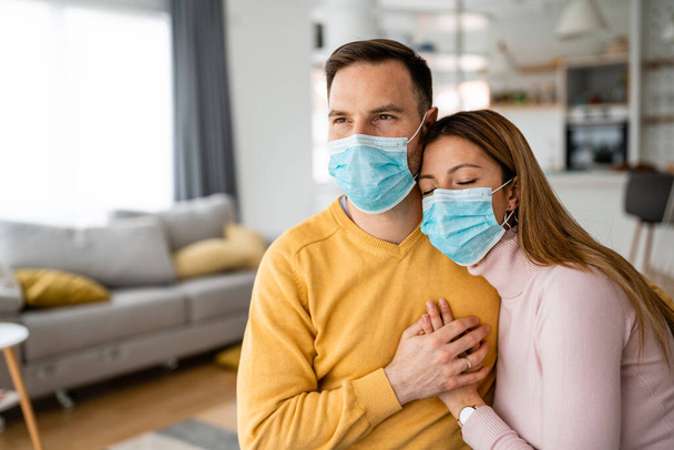 Home isolation during coronavirus quarantine. Man and woman wearing face mask. Coronavirus protection and prevention. Stay home - 写真・画像