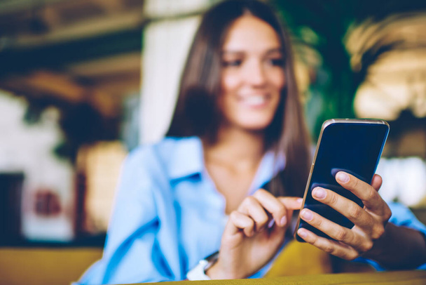 Επιλεκτική εστίαση στο γυναικείο χέρι με σύγχρονο κινητό τηλέφωνο συνομιλίας με τους φίλους μέσω της εφαρμογής κατά τη διάρκεια του ελεύθερου χρόνου, γυναίκα πληκτρολογώντας μήνυμα κειμένου για την αποστολή σε απευθείας σύνδεση μέσω smartphone gadget σε εσωτερικούς χώρους - Φωτογραφία, εικόνα