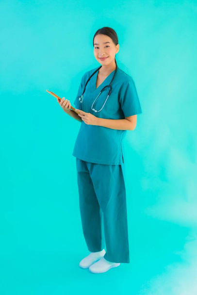 Ritratto bella giovane donna medico asiatico con cartone vuoto per copiare spazio su sfondo blu isolato - Sanità in ospedale e concetto clinica
 - Foto, immagini