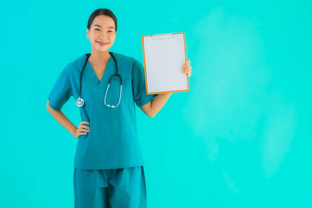 Portrait beautiful young asian doctor woman with empty paper board for copy space on blue isolated background - Healthcare in hospital and clinic concept - Photo, Image