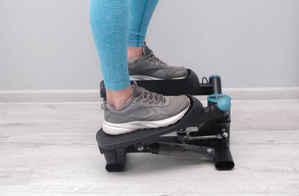 Ноги женщины, упражняющейся на поворотнике ступеньки. Цифровой дисплей, поддерживающий форму дома
.  - Фото, изображение