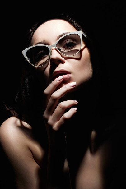 Piękna kobieta w okularach. Portret w stylu retro. Lady Dziewczyna patrząc z ciemności - Zdjęcie, obraz