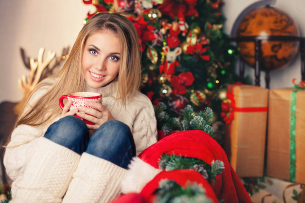 Young woman with a cup near christmas tree - Fotoğraf, Görsel