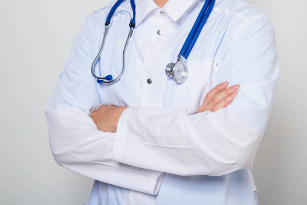 Close-up of a male doctor in a white coat with a stethoscope on his neck, standing with his arms crossed on his chest. One on a white background. - Photo, Image
