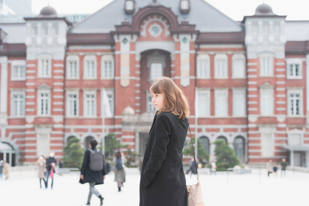 Молодая женщина осматривает кирпичную станцию Токио (Токио, Япония)
) - Фото, изображение