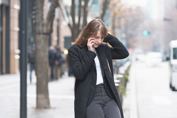 Καυκάσια νεαρή γυναίκα μιλάει με κάποιον με smartphone στο αυτί - Φωτογραφία, εικόνα