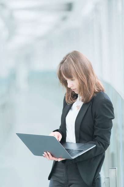Portrait of young business woman with laptop in business district - Foto, Imagen
