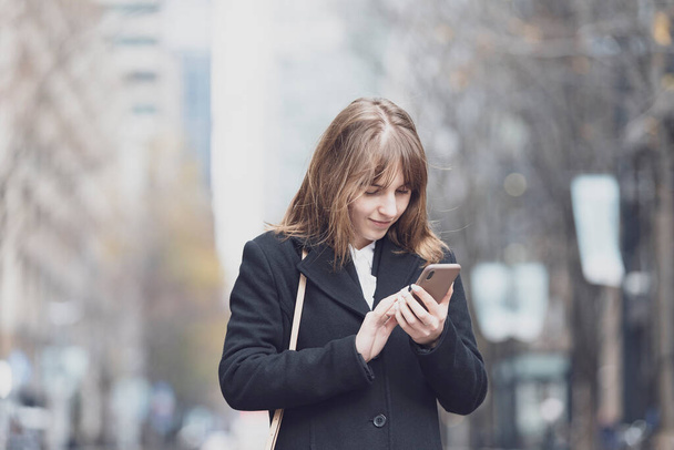 Mujer joven usando smartphone en la calle de la ciudad
 - Foto, imagen