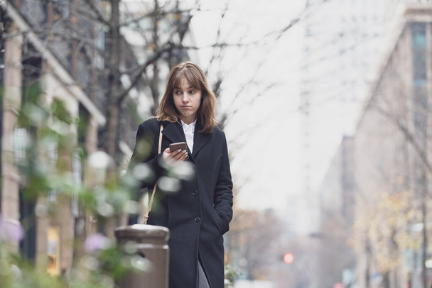 Mujer joven usando smartphone en la calle de la ciudad
 - Foto, Imagen