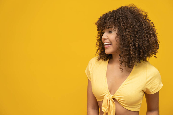 Mujer rizada latina joven posando sobre fondo amarillo brillante
 - Foto, Imagen