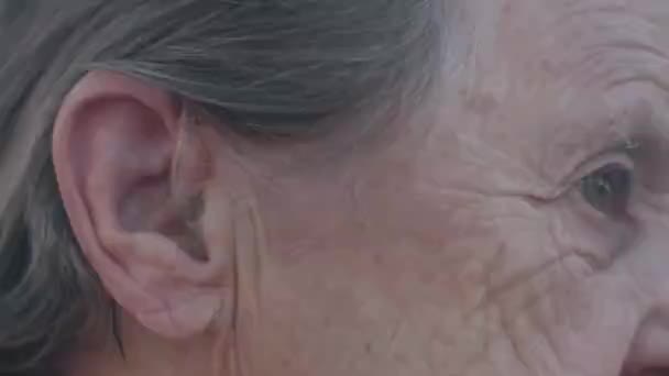 Dicht zicht op het gezicht van een oude vrouw met gehoorapparaat - Video