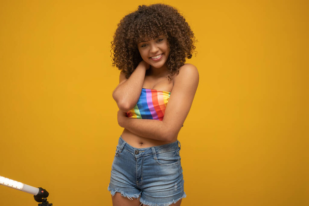 Mujer rizada latina joven posando con bandera LGBT arco iris
 - Foto, Imagen