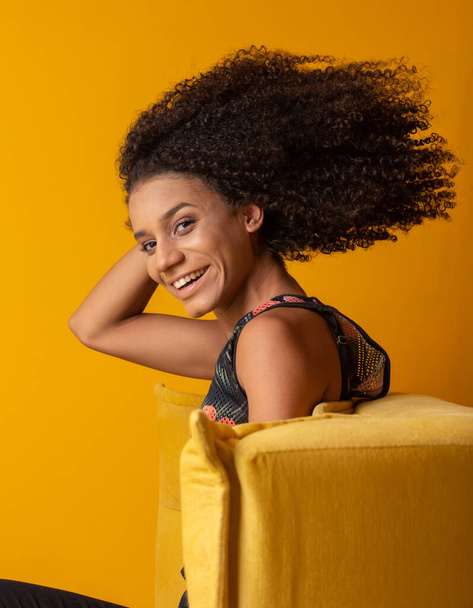 Mujer afroamericana joven con el pelo rizado mirando a la cámara y sonriendo. Linda chica afro con el pelo rizado sonriendo mirando a la cámara
. - Foto, imagen