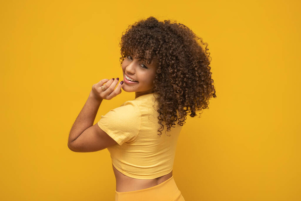 Young latin curly woman posing on bright yellow background - Photo, Image