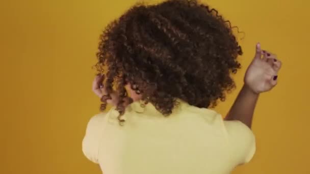 Young brazil curly woman gesturing and posing on yellow background - Filmmaterial, Video
