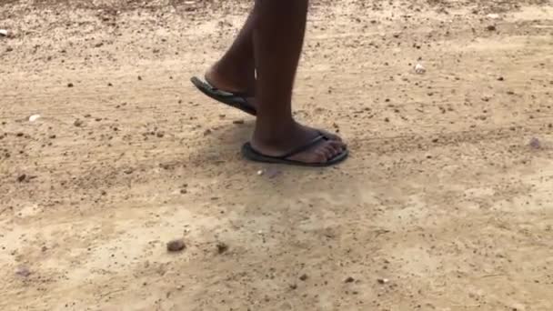 Близкий вид черного человека, идущего по земле в шлепанцах
 - Кадры, видео