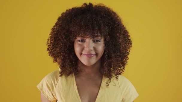 Молода бразилія кучерява жінка жестикулює і позує на жовтому фоні
 - Кадри, відео