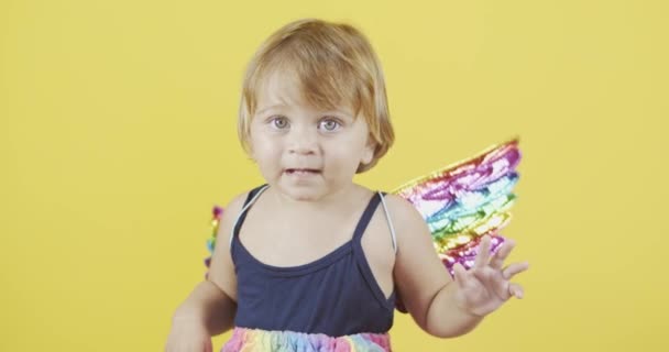 Nettes Mädchen mit Engelsflügeln posiert auf gelbem Hintergrund - Filmmaterial, Video