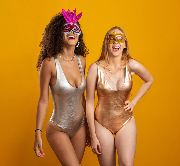 Schöne Frauen, die sich für den Karneval verkleidet haben. Lächelnde Frauen, die bereit sind, die Fasnet mit einer bunten Maske zu genießen. Aufzeigen. - Foto, Bild